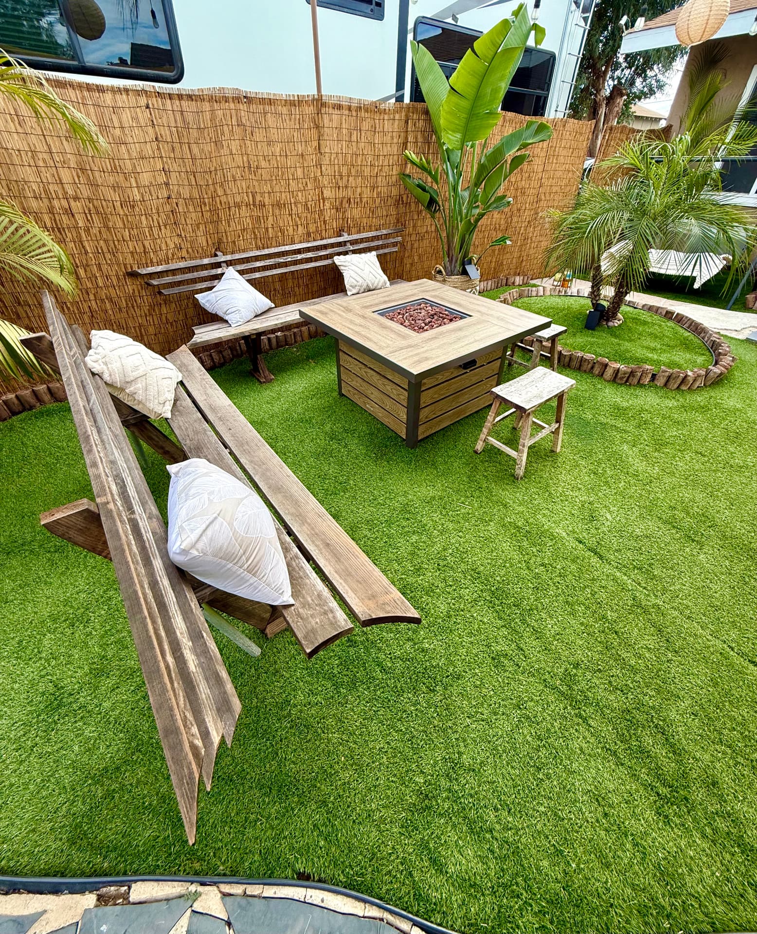 Fire pit table with wooden benches on Casa Tulum's turf lawn
