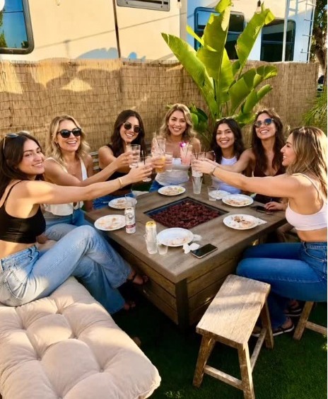 Group cheering with cocktails around the fire pit table