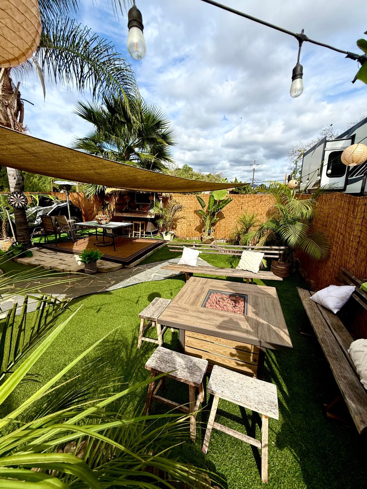 Casa Tulum's turf yard with fire pit table, shade sails and palms